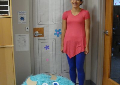 Picture of CT staff member Johanna McGough-Pose dressed as Boo from Monsters Inc next to door decorated like Boo's door in Monsters Inc