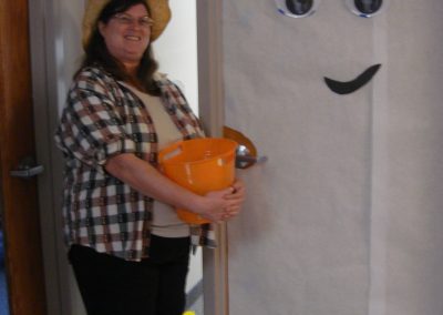 Picture of CT staff member Lori Michaud dressed as farmer with straw hat and plaid shirt. Door decorated as a happy ghost.