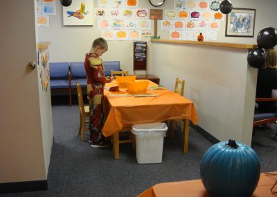 Picture of child dressed as Iron Man decorating a paper pumpkin with stickers