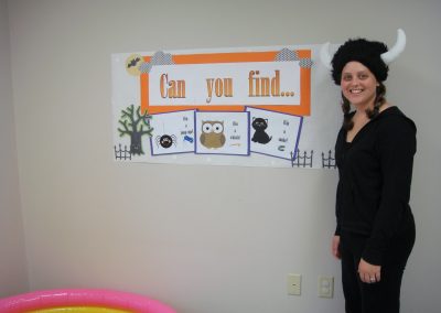 Picture of CT staff member Tricia Madison dressed in black with hat with horns and Halloween decoration